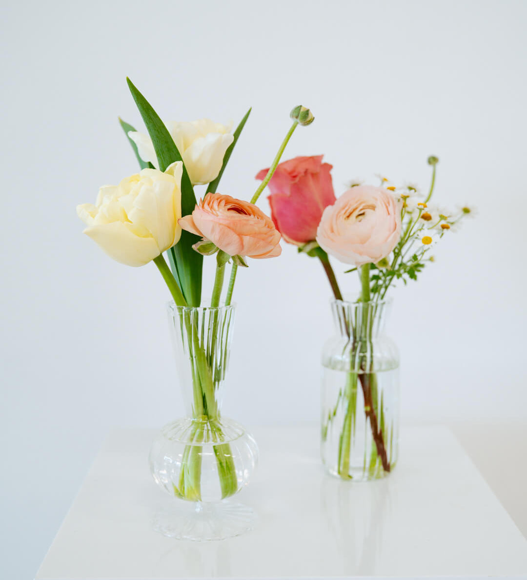 Bud vase sized spring flower arrangement set in a bud vase on a white pedestal and neutral background. Available for same day local delivery and pickup in Columbus Ohio 
