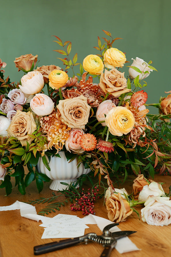 Bouquet of flowers in a white vase on a wooden table with floral shears in Columbus, Ohio