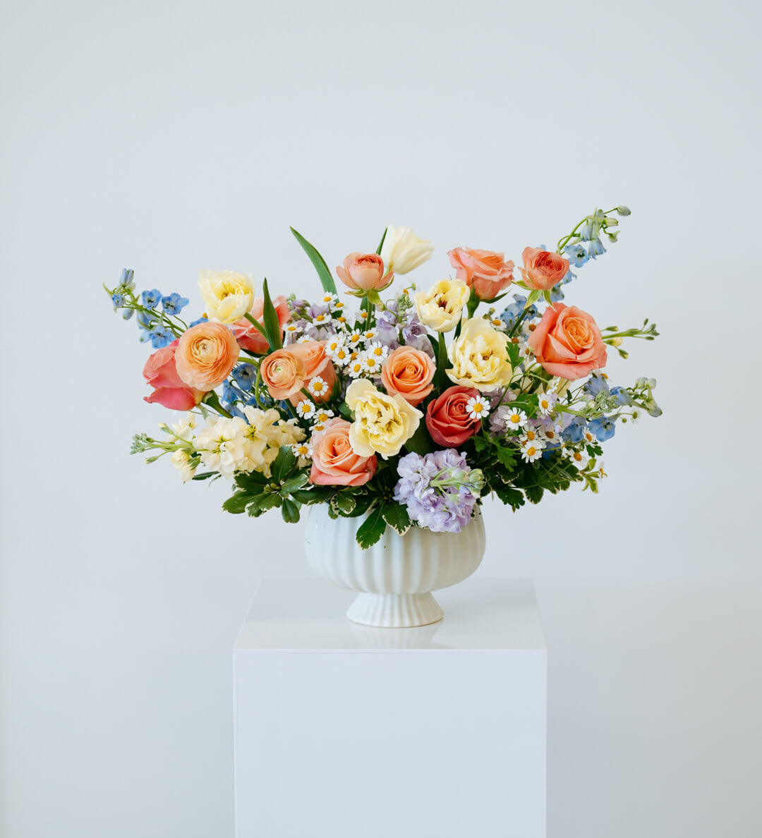Luxe Grand sized spring flower arrangement set in a white vase on a white pedestal and neutral background. Available for sameday local delivery and pickup in Columbus Ohio 