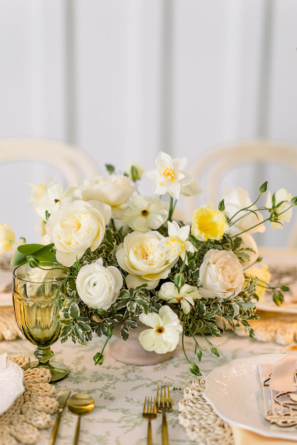 A beautifully arranged table setting featuring white flowers and vibrant green accents.