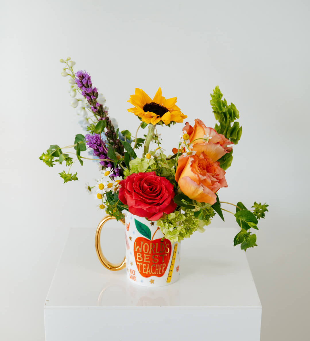 Colorful bouquet of flowers in a mug that reads Worlds Best Teacher available for local pickup and delivery in Columbus Ohio for teacher appreciation gifting