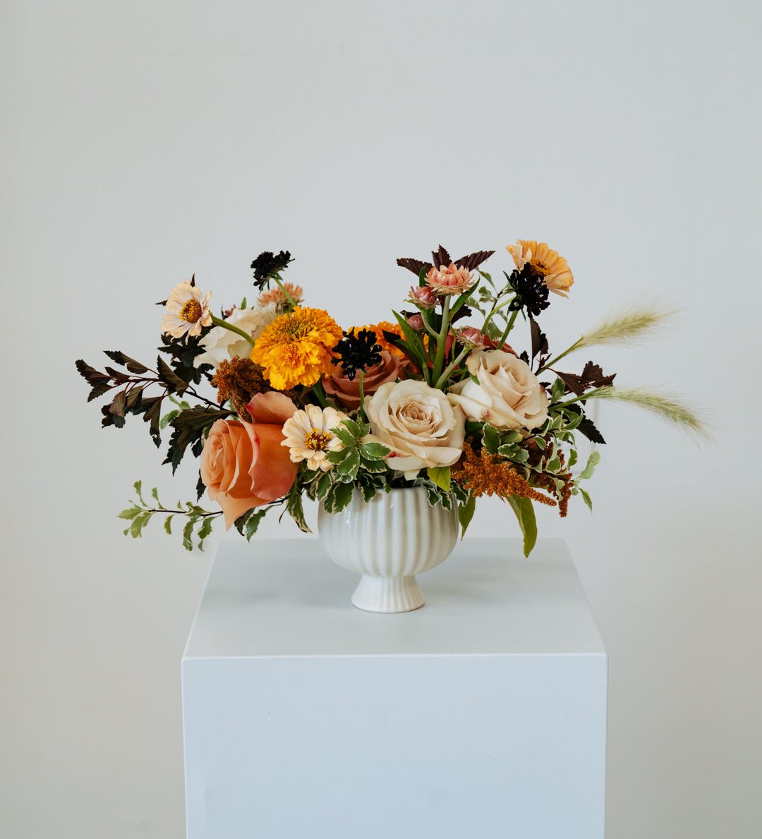 Floral arrangement in a white vase on a pedestal against a plain background available for local delivery and pick-up in Central, Ohio