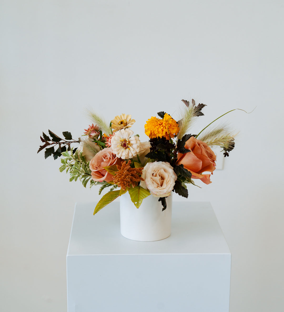 Floral arrangement in a white vase on a light blue pedestal against a white background available for local delivery and pick-up in Central, Ohio