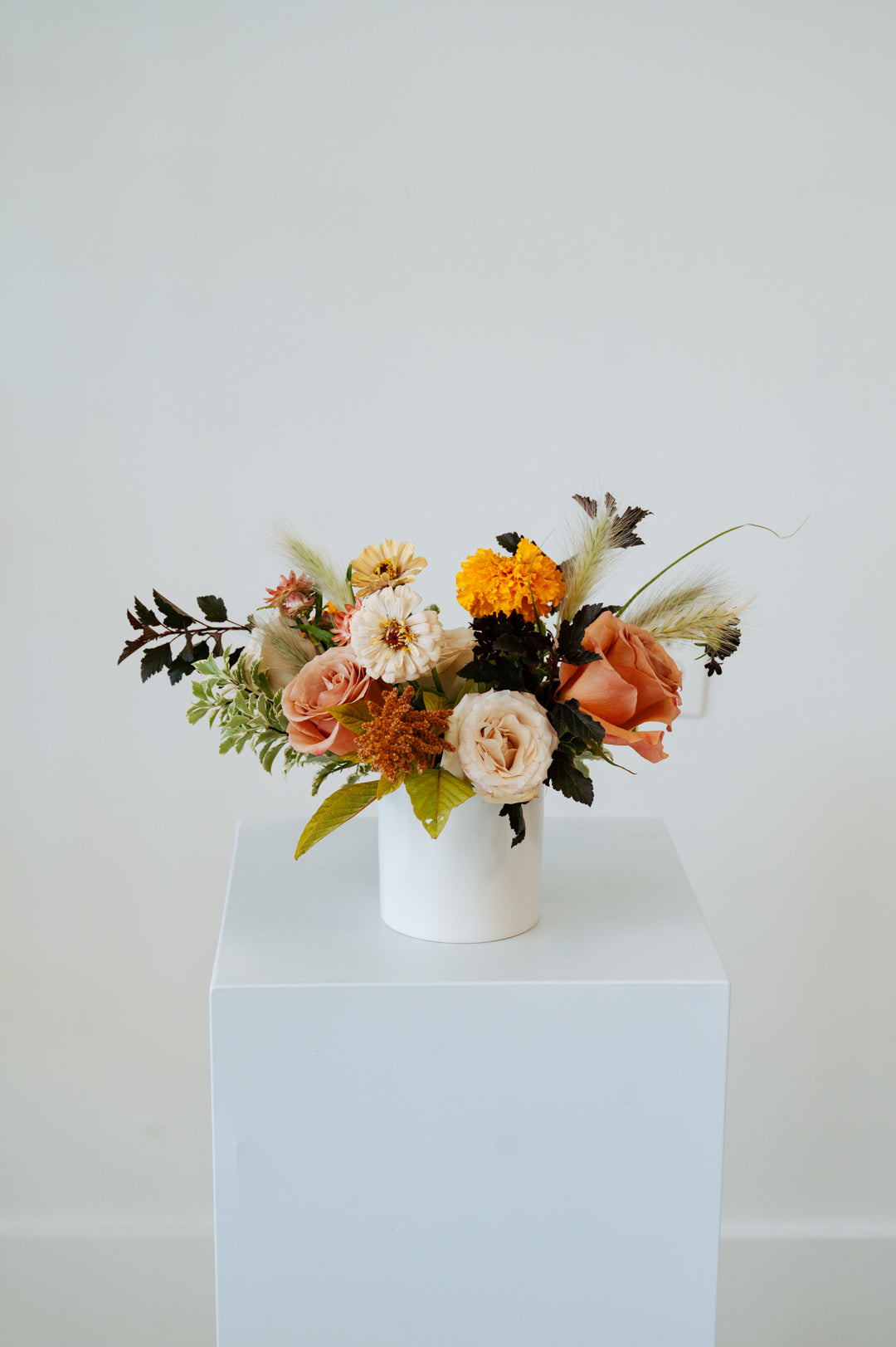Floral arrangement in a white vase on a light blue pedestal against a white background available for local delivery and pick-up in Central, Ohio