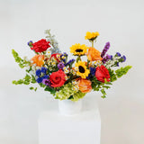 Colorful bouquet of flowers in a white vase on a light gray background