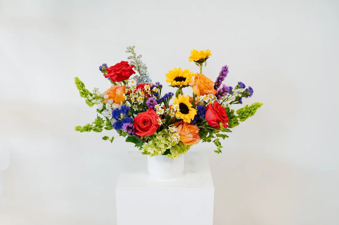 Colorful bouquet of flowers in a white vase on a light gray background