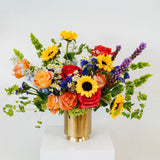 Colorful flower arrangement in a gold vase on a white background