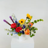 Colorful flower arrangement in a white vase on a light gray background