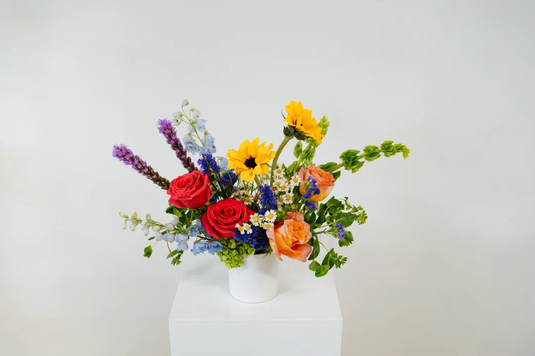 Colorful flower arrangement in a white vase on a light gray background