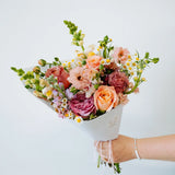 Bouquet of flowers held by a Flocal Co. staff member against a white background