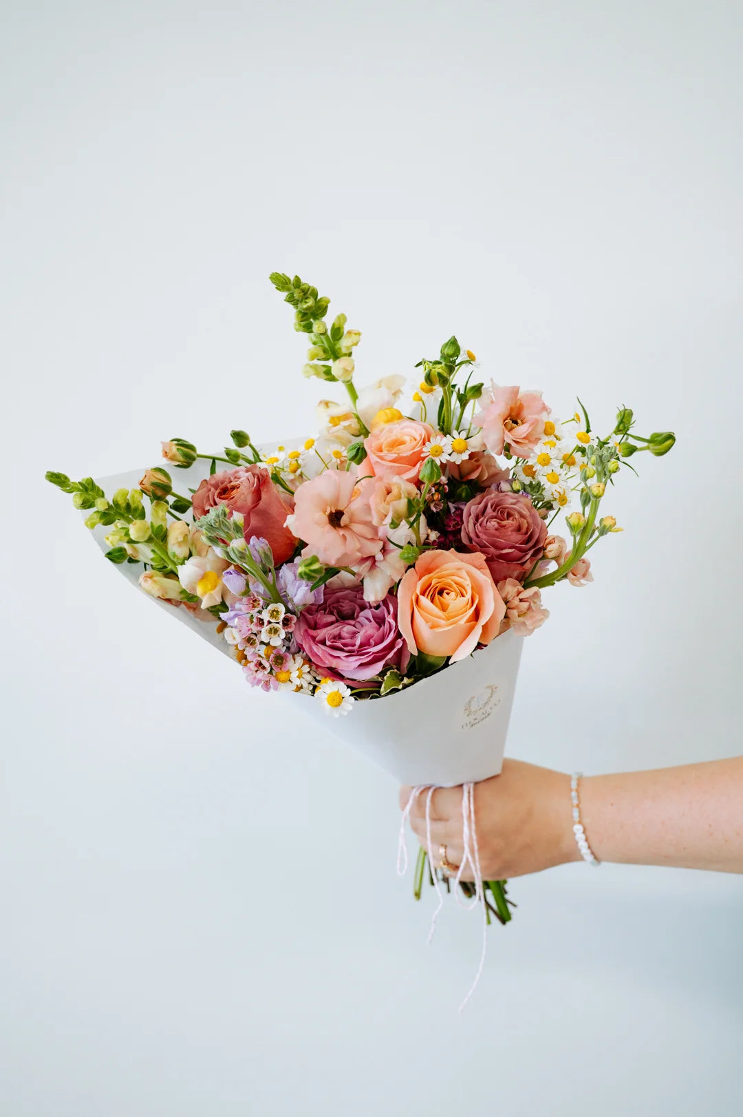 Bouquet of flowers held by a Flocal Co. staff member against a white background