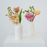 Bud Vase sized spring flower arrangement set in a white vase on a white pedestal and neutral background. Available for same day local delivery and pickup in Columbus Ohio 