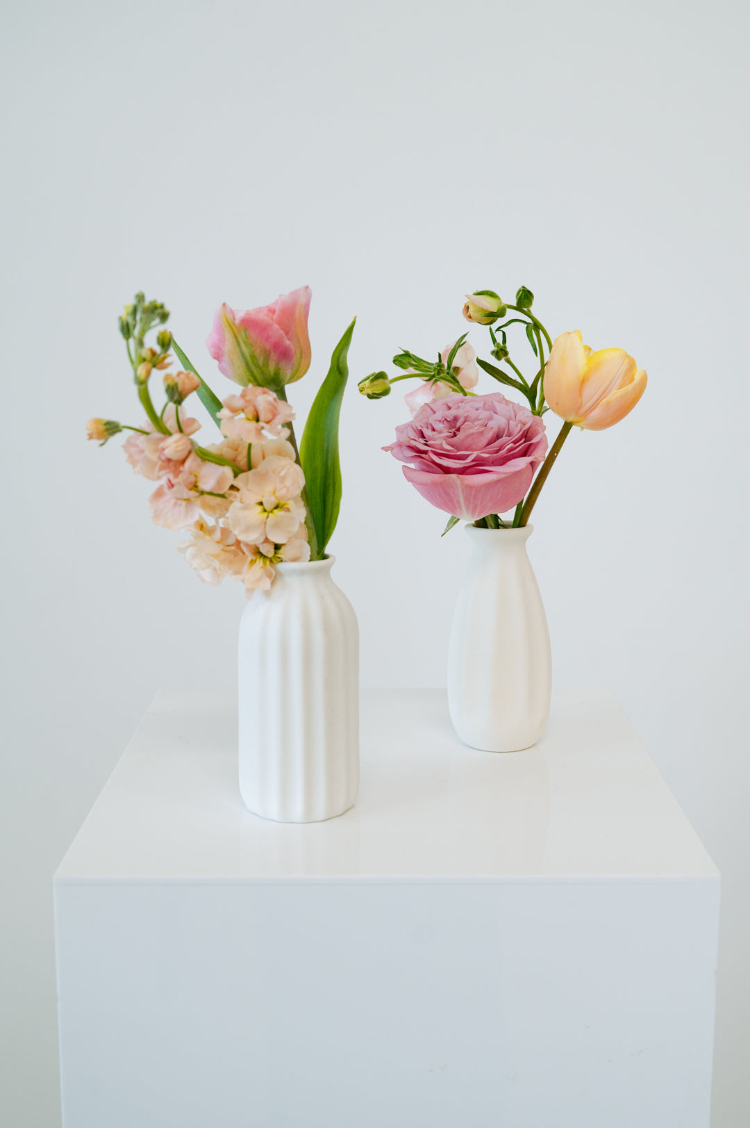 Bud Vase sized spring flower arrangement set in a white vase on a white pedestal and neutral background. Available for same day local delivery and pickup in Columbus Ohio 