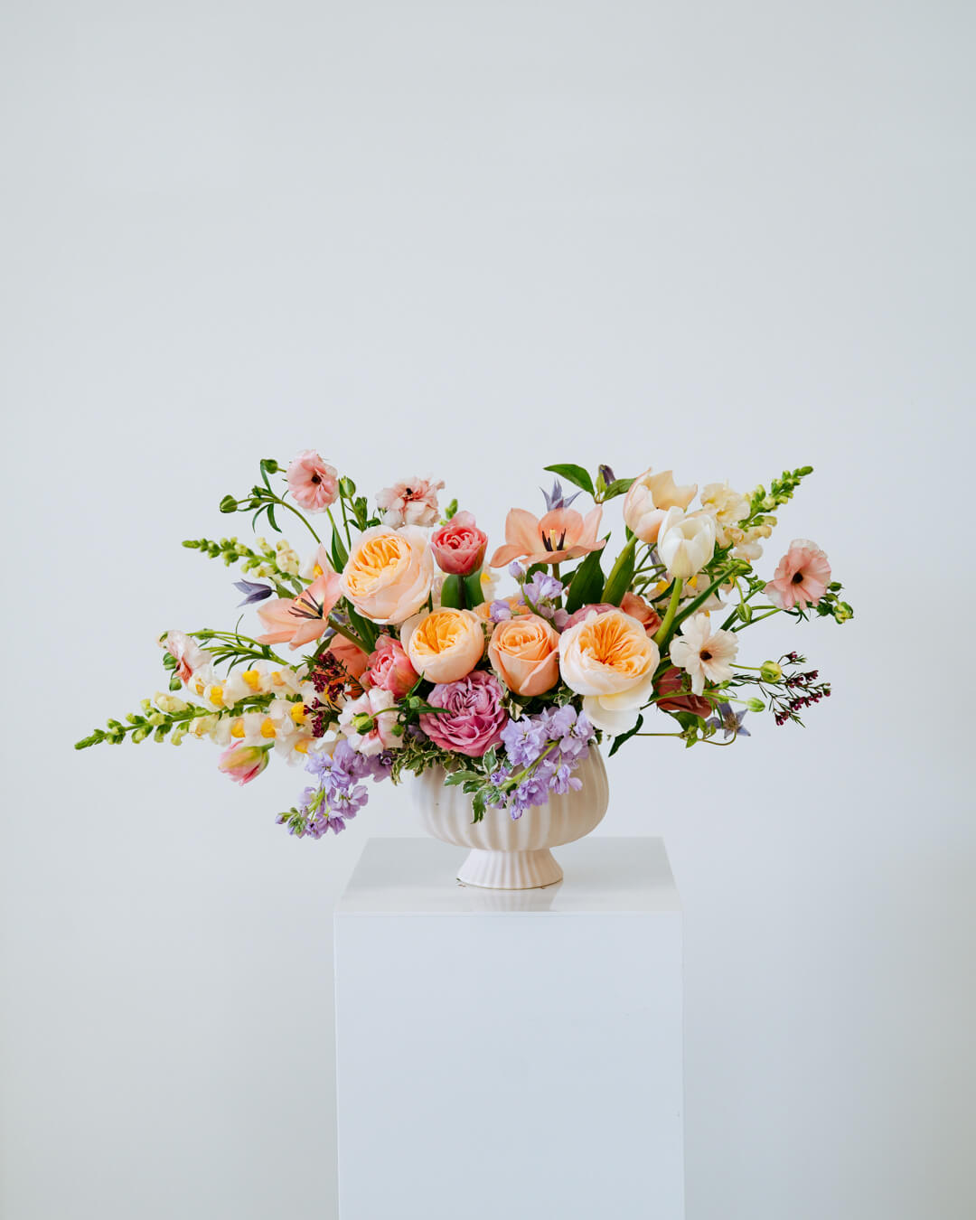 Luxe Grand sized spring flower arrangement set in a white vase on a white pedestal and neutral background. Available for same day local delivery and pickup in Columbus Ohio 