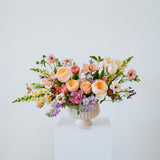 Luxe Grand sized spring flower arrangement set in a white vase on a white pedestal and neutral background. Available for same day local delivery and pickup in Columbus Ohio 