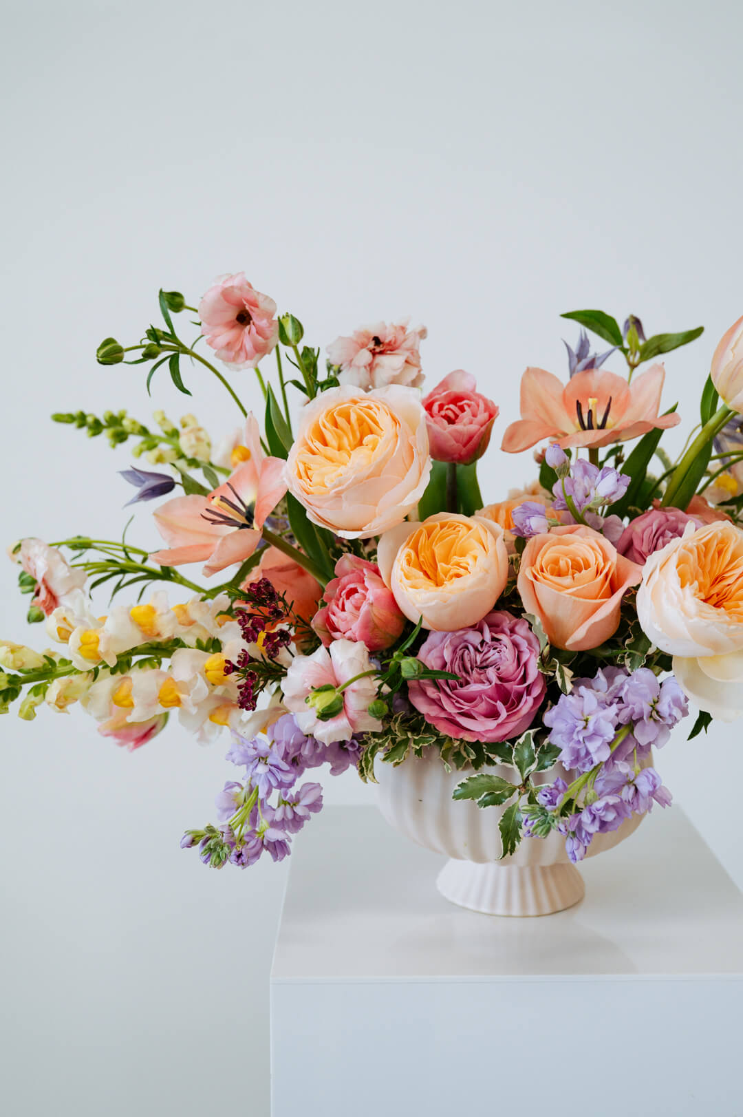 Luxe Grand sized spring flower arrangement set in a white vase on a white pedestal and neutral background. Available for same day local delivery and pickup in Columbus Ohio 
