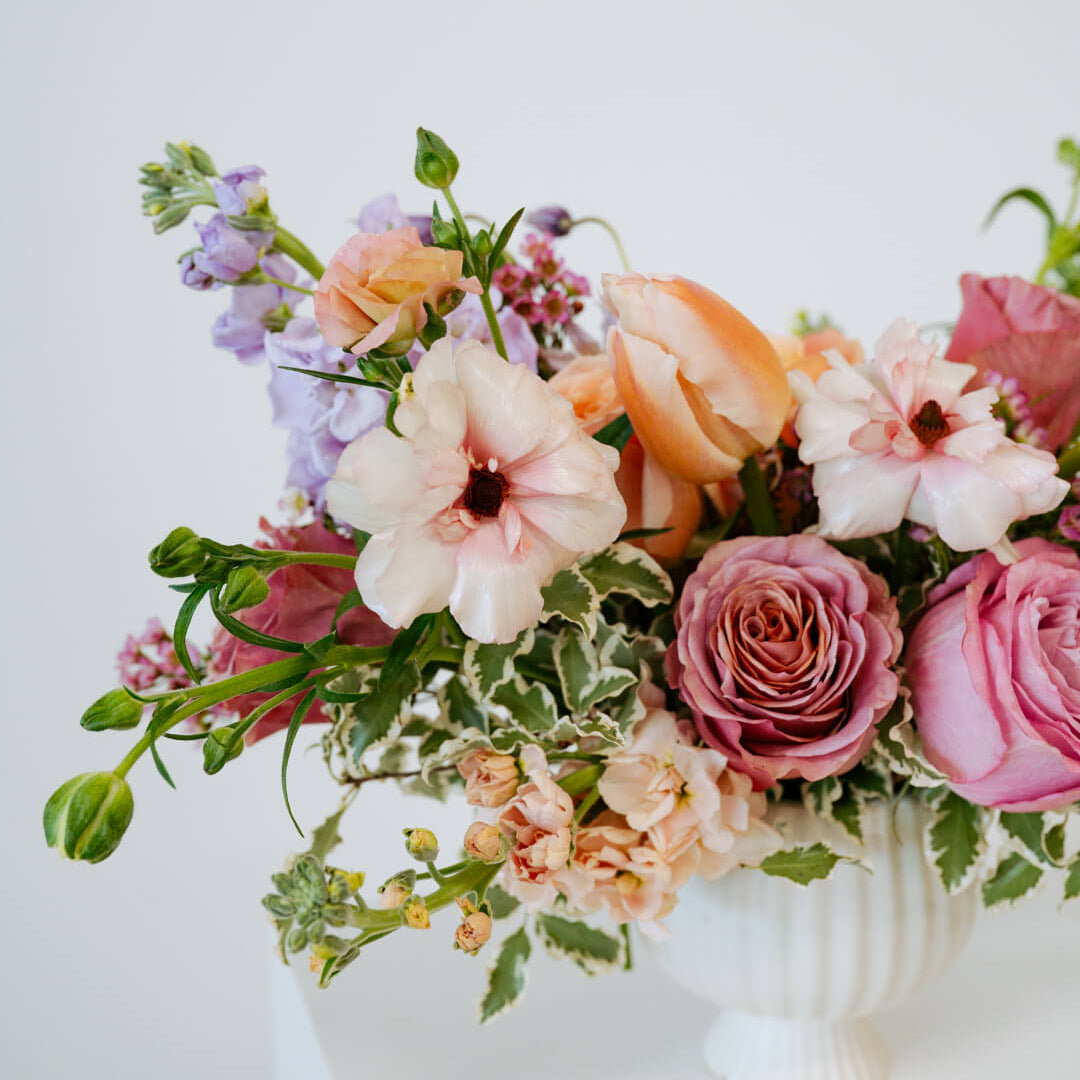 Medium sized spring flower arrangement set in a white vase on a white pedestal and neutral background. Available for same day local delivery and pickup in Columbus Ohio 