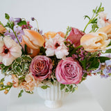 Medium sized spring flower arrangement set in a white vase on a white pedestal and neutral background. Available for same day local delivery and pickup in Columbus Ohio 