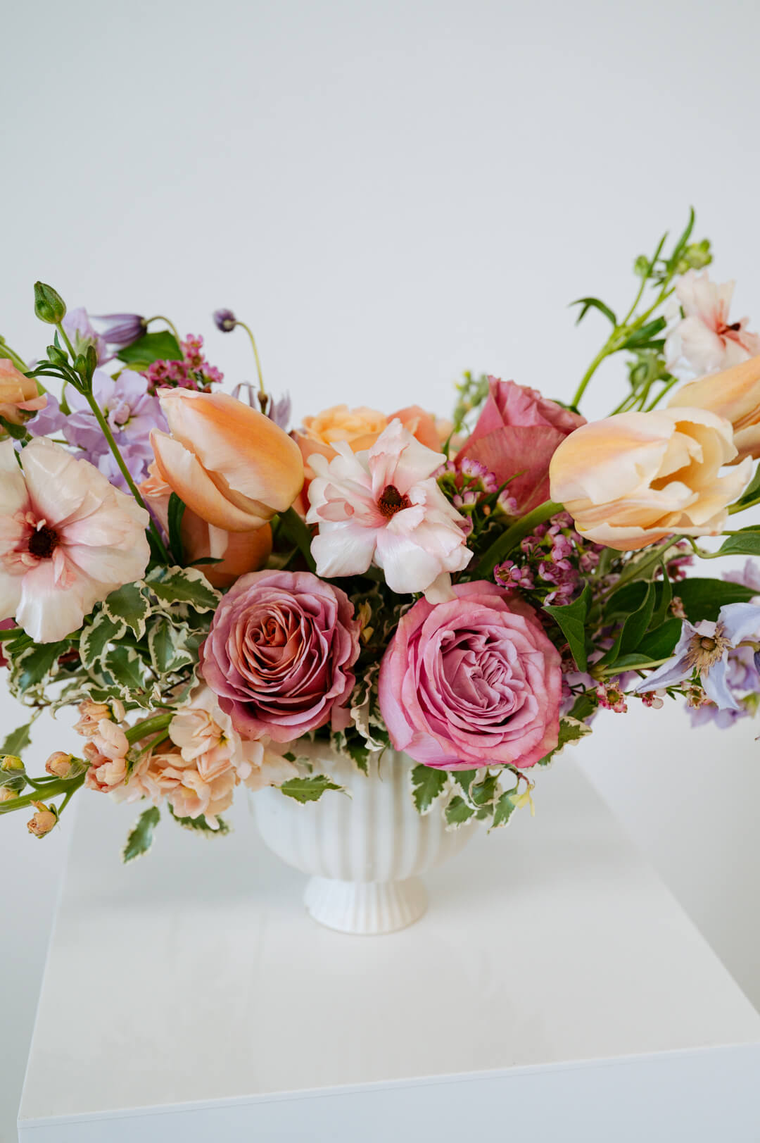 Medium sized spring flower arrangement set in a white vase on a white pedestal and neutral background. Available for same day local delivery and pickup in Columbus Ohio 