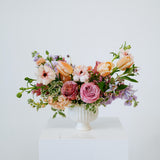 Medium sized spring flower arrangement set in a white vase on a white pedestal and neutral background. Available for same day local delivery and pickup in Columbus Ohio 