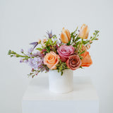 Petite sized spring flower arrangement set in a white vase on a white pedestal and neutral background. Available for same day local delivery and pickup in Columbus Ohio 