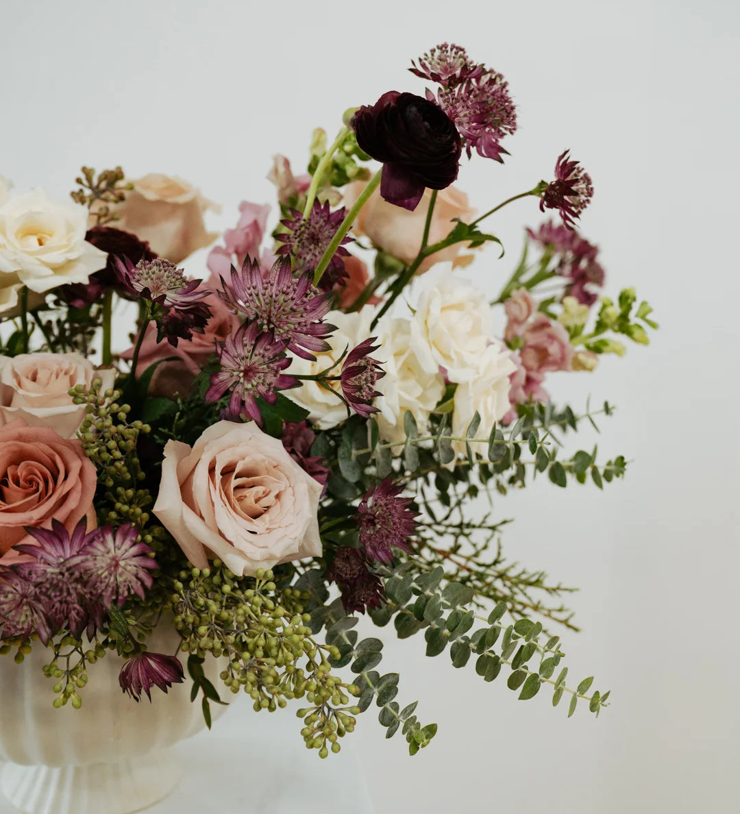 Columbus Ohio floral arrangement with pink, purple, and white flowers in a white vase on a light background