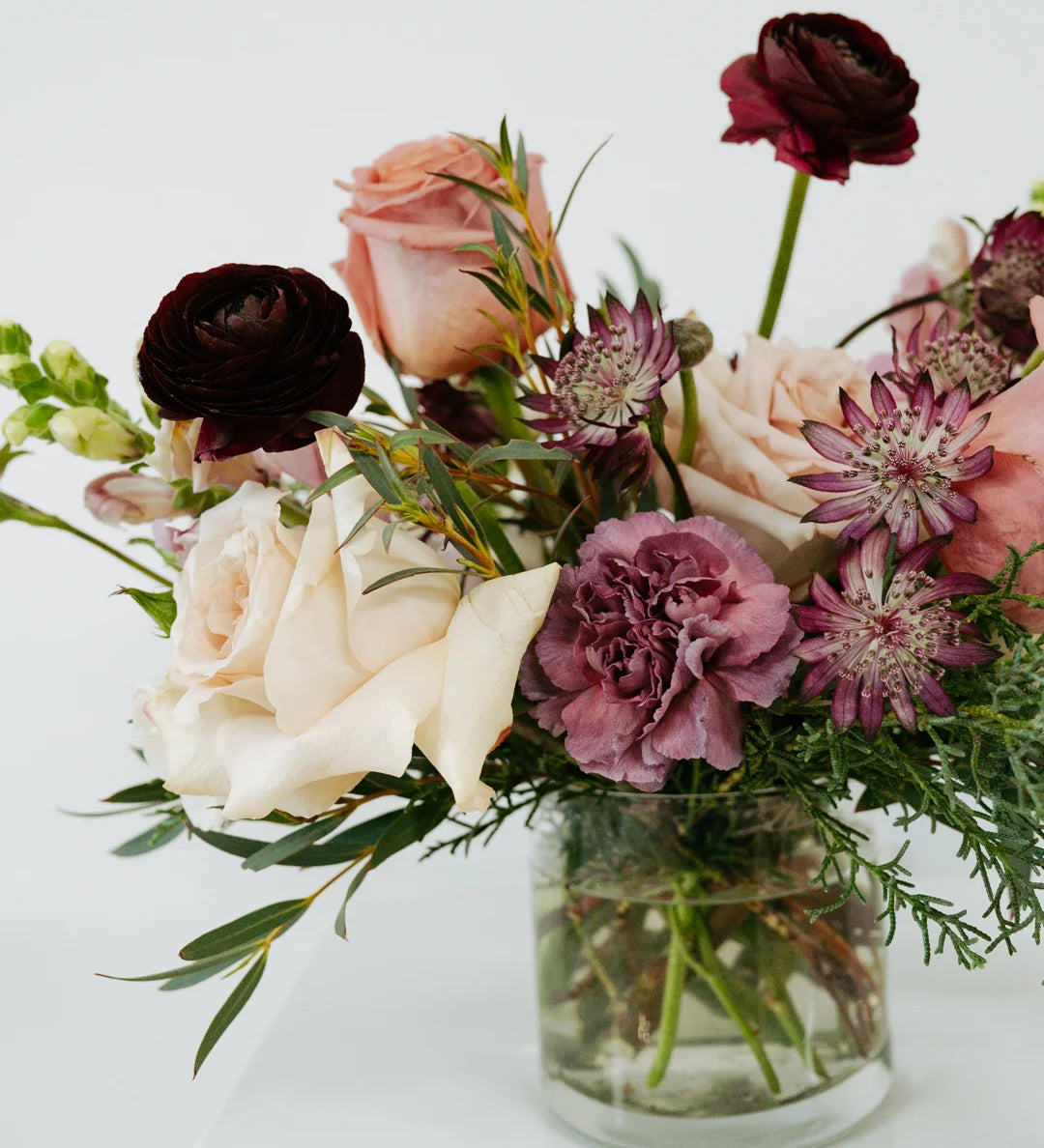 Mauve colored bouquet of flowers in a glass vase on a white background 