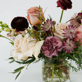 Mauve colored bouquet of flowers in a glass vase on a white background 