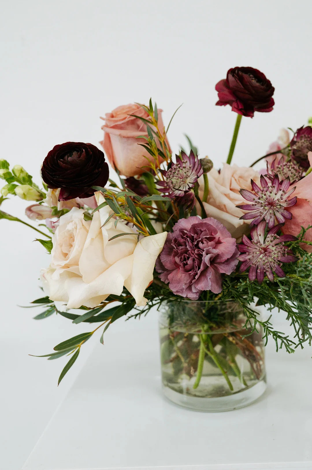 Mauve colored bouquet of flowers in a glass vase on a white background 