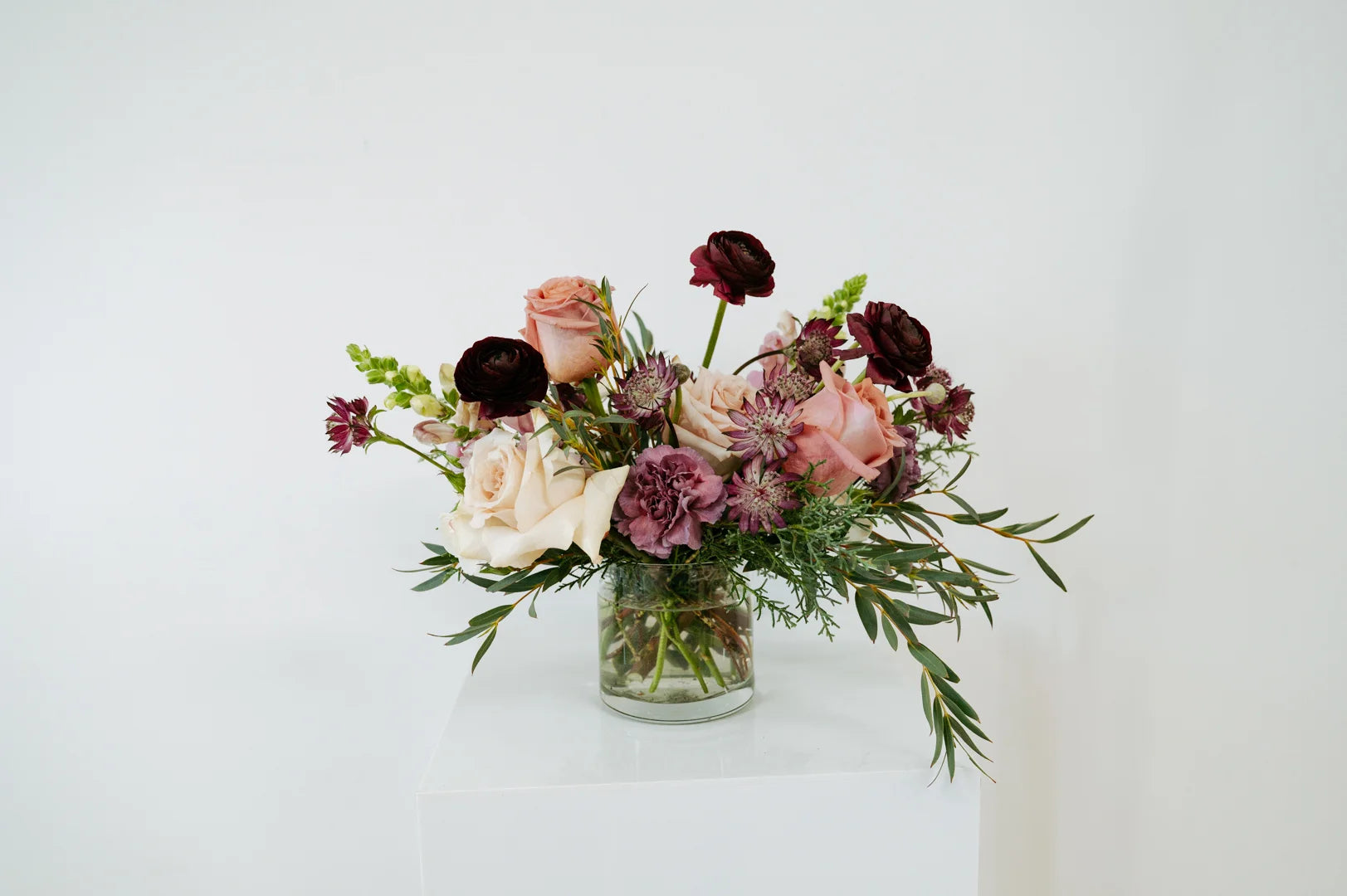 Flocal Co's moody mauve flowers in a clear vase on a white background