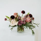 Flocal Co's moody mauve flowers in a clear vase on a white background