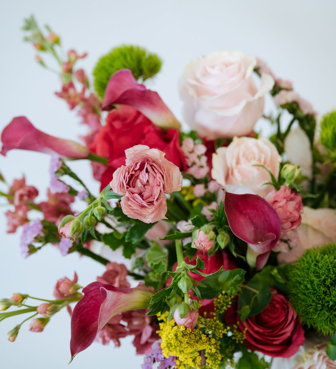 Luxe Grand sized spring flower arrangement set in a white vase on a white pedestal and neutral background. Available for same day local delivery and pickup in Columbus Ohio 