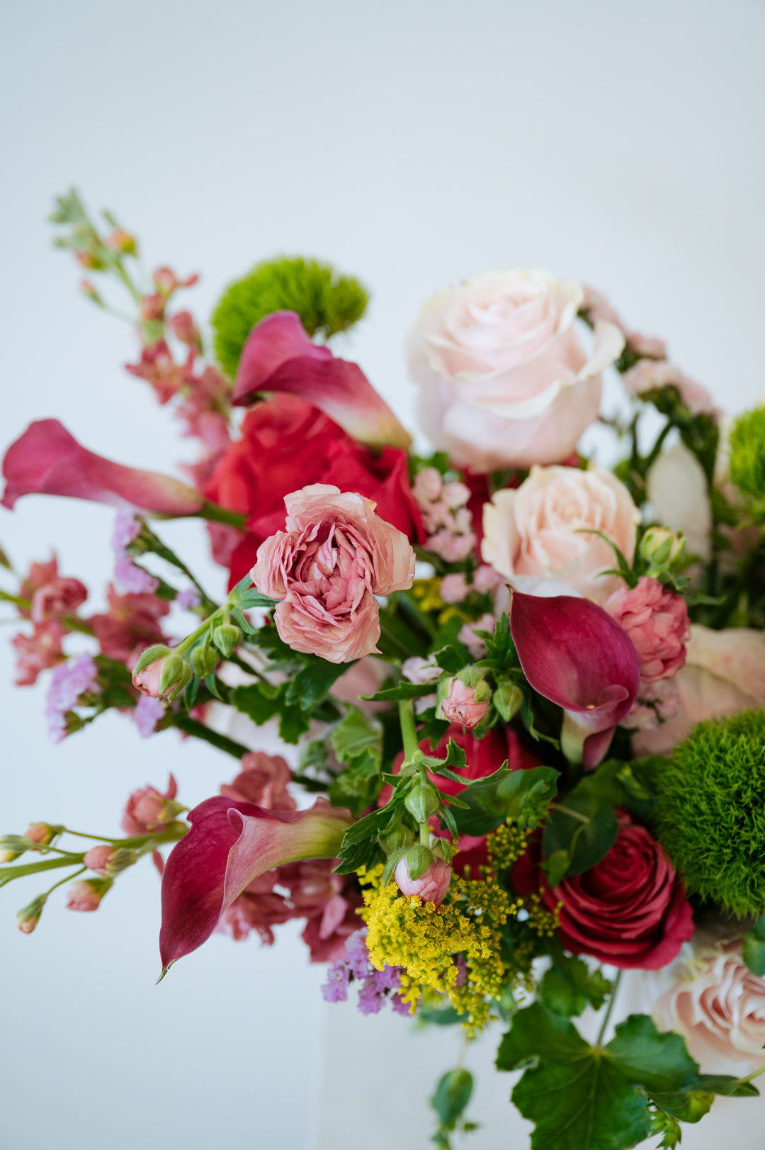 Luxe Grand sized spring flower arrangement set in a white vase on a white pedestal and neutral background. Available for same day local delivery and pickup in Columbus Ohio 