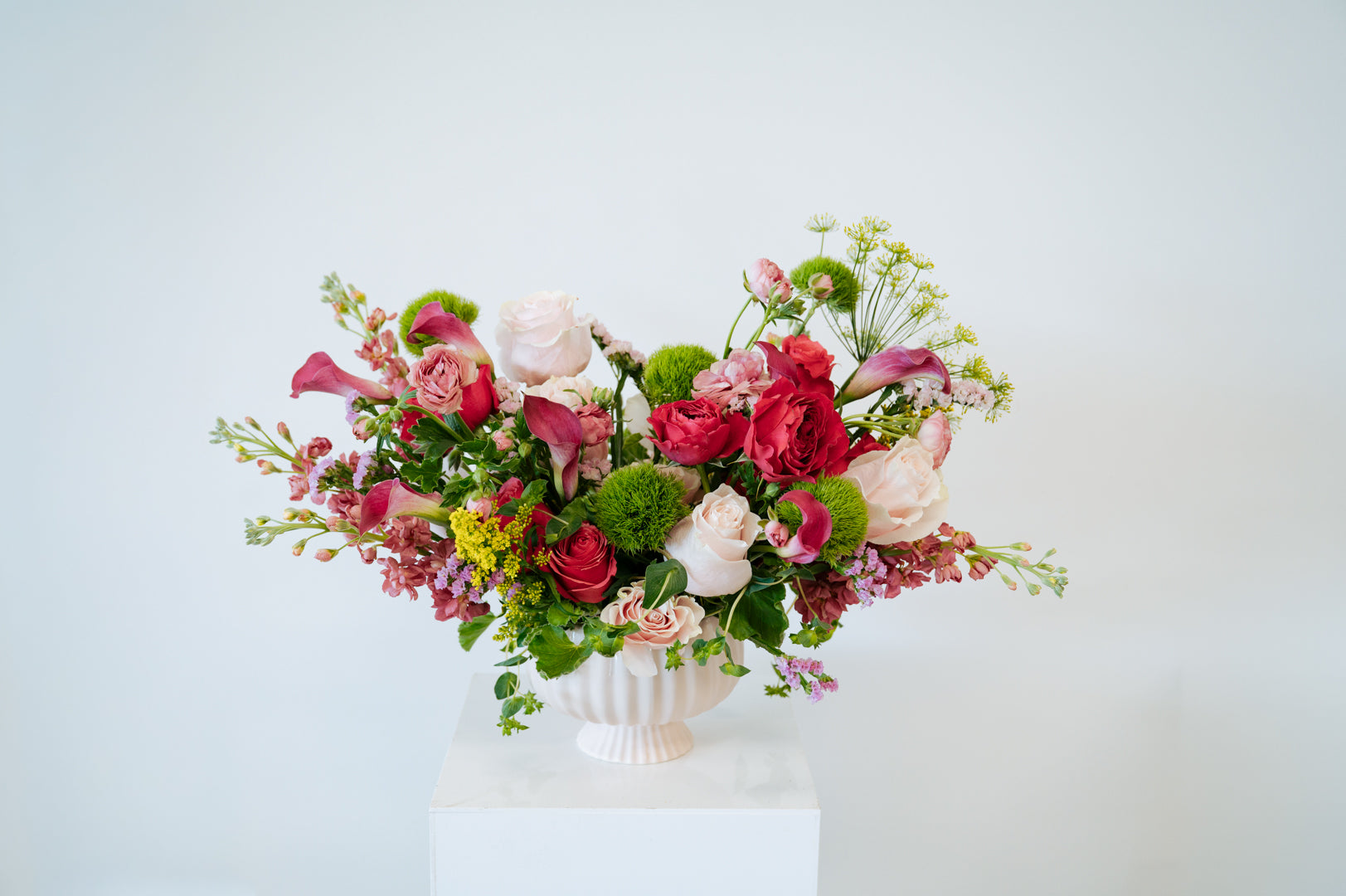 Luxe Grand sized spring flower arrangement set in a white vase on a white pedestal and neutral background. Available for same day local delivery and pickup in Columbus Ohio 