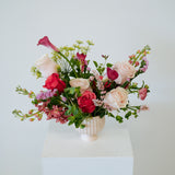 Medium compote sized spring flower arrangement set in a neutral mini compote on a white pedestal and neutral background. Available for same day local delivery and pickup in Columbus Ohio 