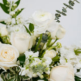 Bouquet of white flowers with green leaves on a light background