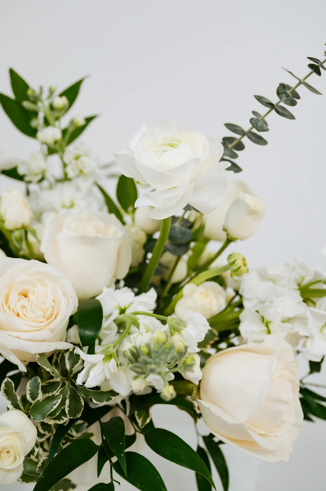 Bouquet of white flowers with green leaves on a light background